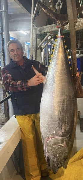 Fisherman standing next to huge tuna fish