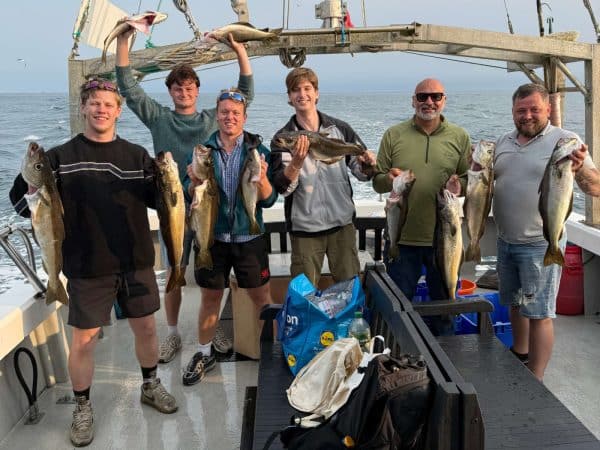 Fishermen holding up their catch on a boat at sea
