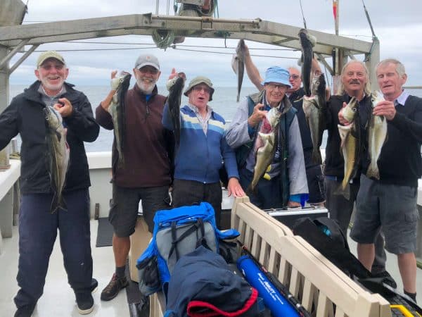 Fishermen holding up their catch on a boat at sea