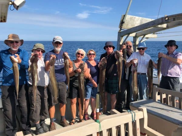 Fishermen holding up their catch on a boat at sea